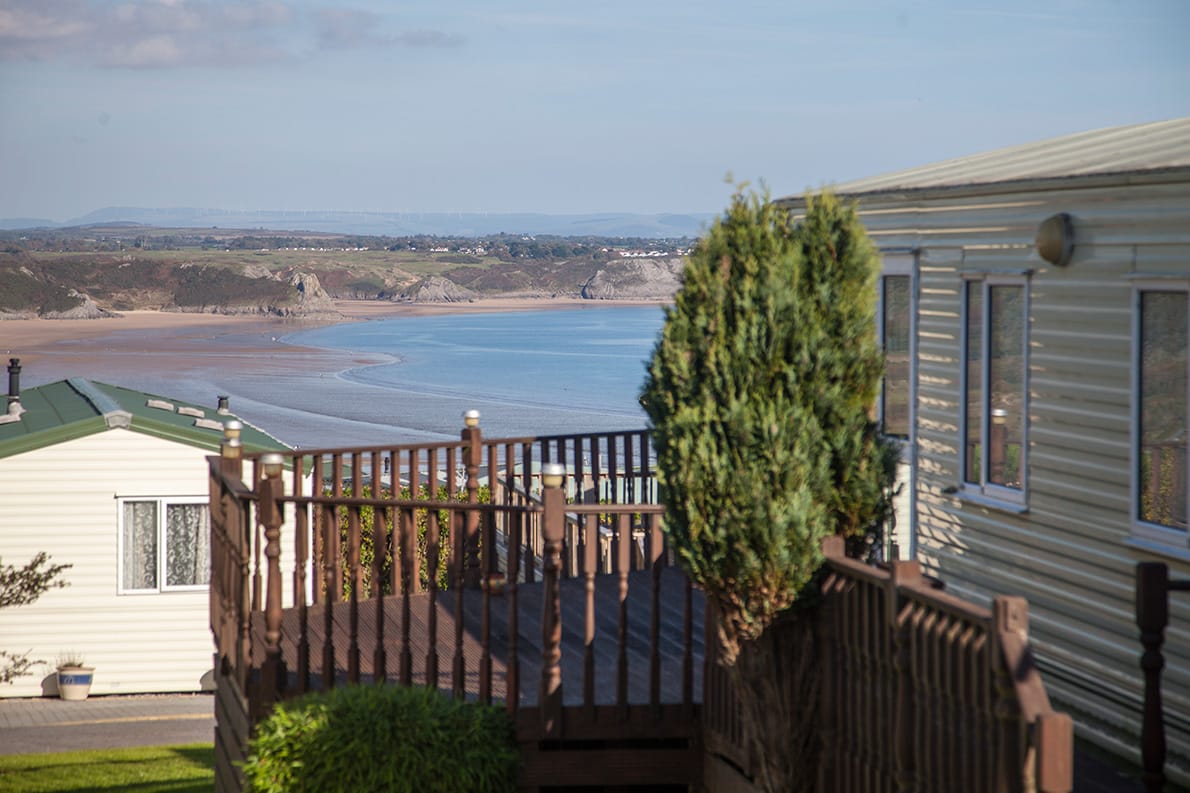 Static caravan with decking overlooking Oxwich Bay